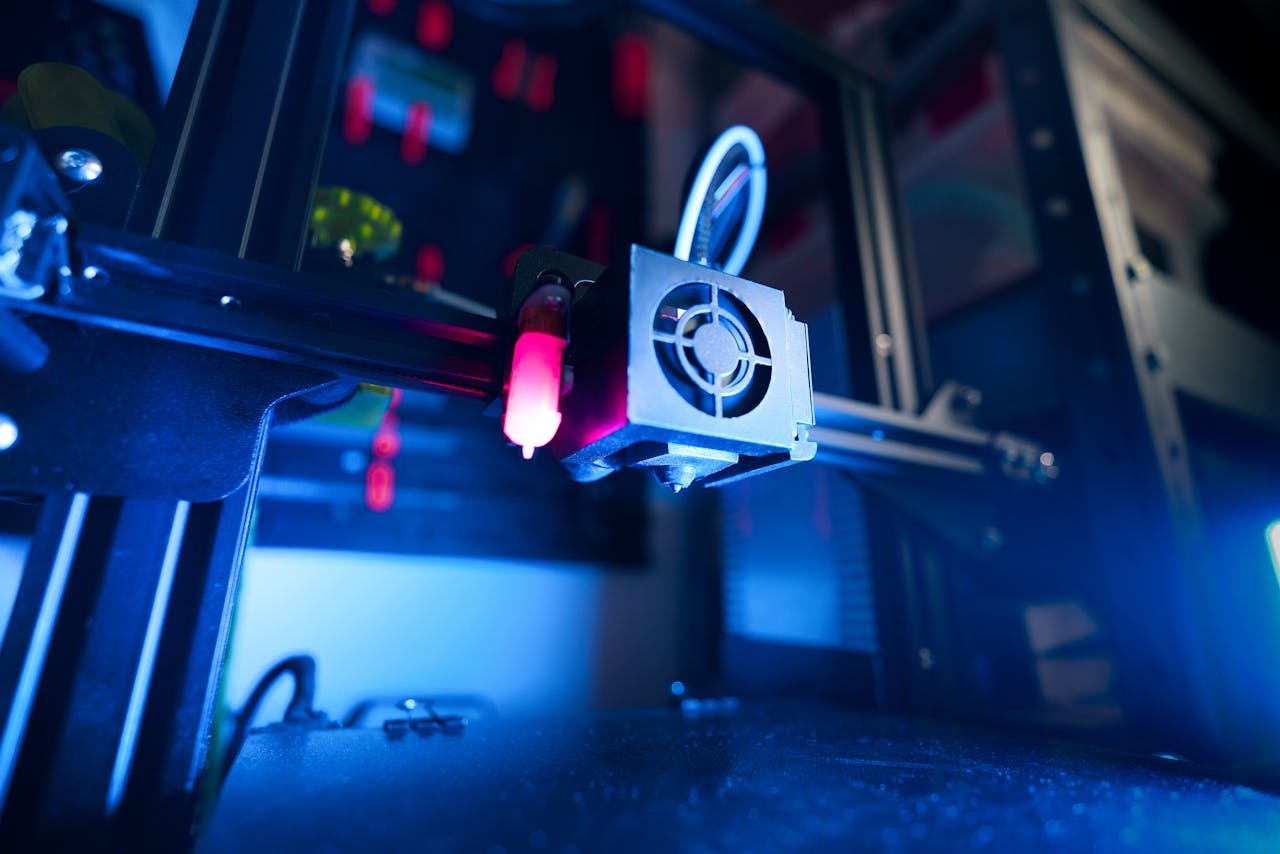 services-02 A close-up of an illuminated 3D printer in action, highlighting modern technology.