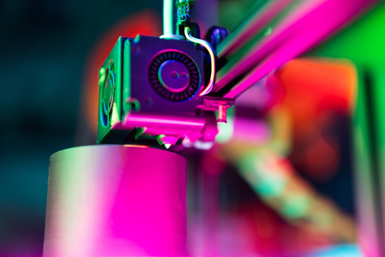 services-04 Close-up of a 3D printer in action under neon lighting, capturing vibrant colors and modern tech ambiance.