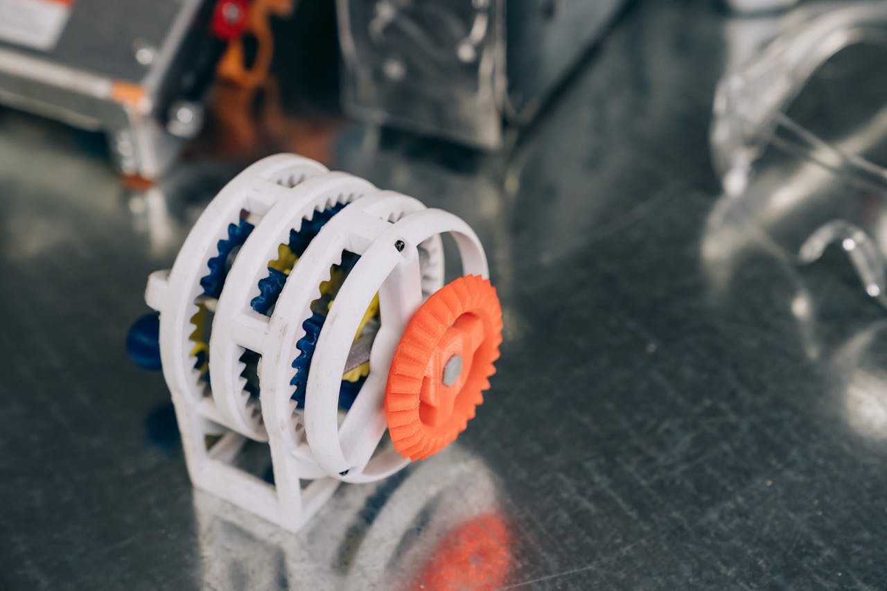 services-03 Close-up of a 3D printed gear mechanism with vibrant colors on a reflective metal surface.